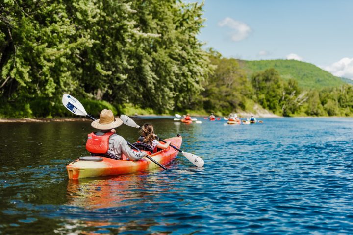 a man riding on the back of a boat next to a lake