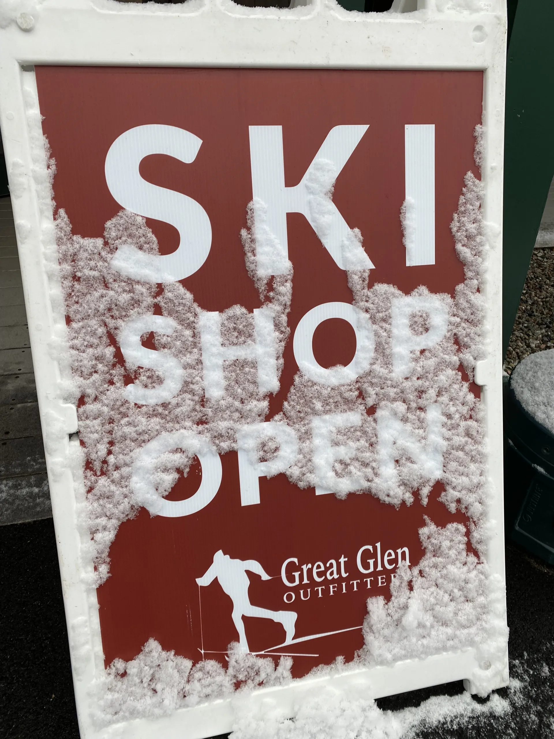 Snow-covered sign reads 'SKI SHOP OPEN' for Great Glen Outfitters.