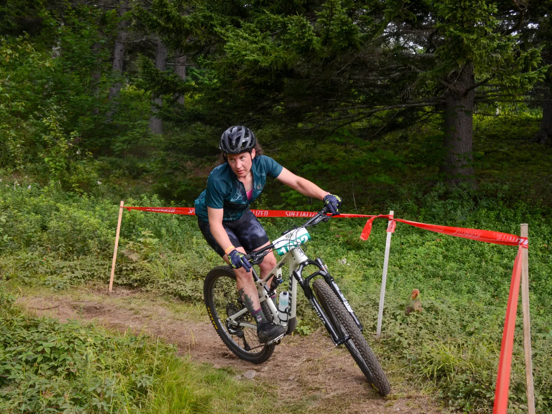 Mountain biker riding on a forest trail with red tape boundaries.